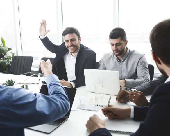 Businessman raising hand and asking question during meeting in office